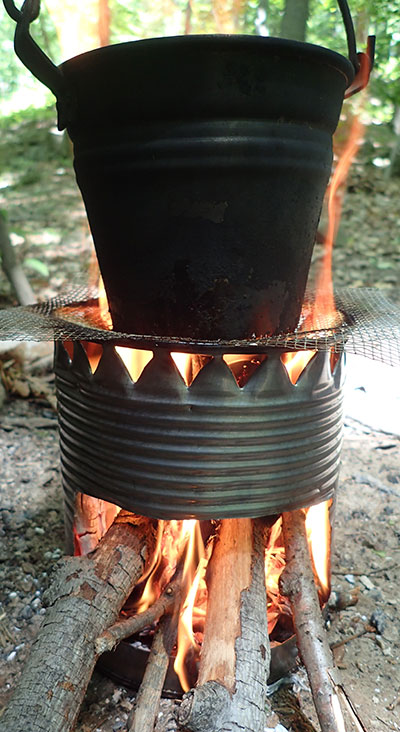 Kettle or pot can be used to boil on top of hobo stove supported by wire fencing or grill. Slide fuel in the side port and push it in as it burns. 