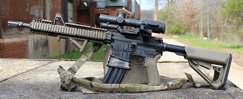 Clone of Gurwitch’s last deployment gun outfitted with same buttstock, pistol grip, forearm, sling, SF four-prong flash hider, offset red dot sight, extended mag well, bolt release, and 1-6X variable scope.