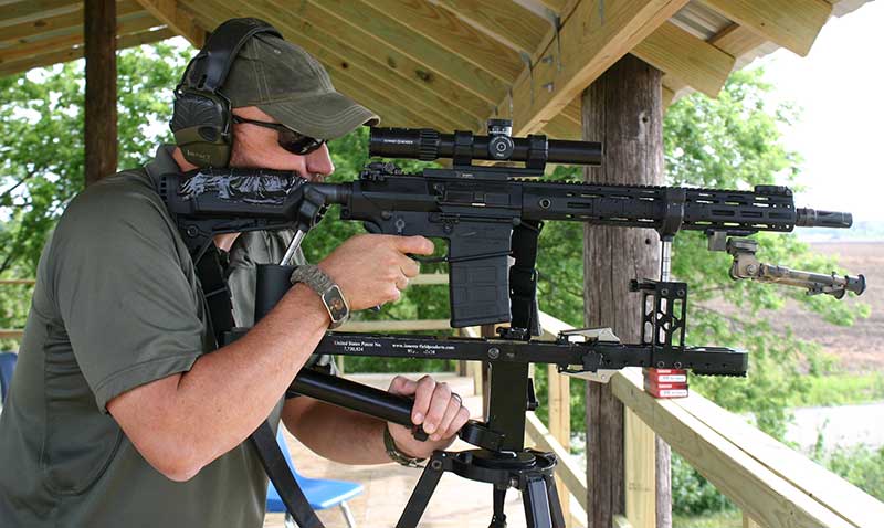 James Ferguson shoots SR-25 E2 ACC from Spec Rest, which clamps rifle into position and holds it firmly in place. This allows rifle to be comfortably and accurately shot from standing.