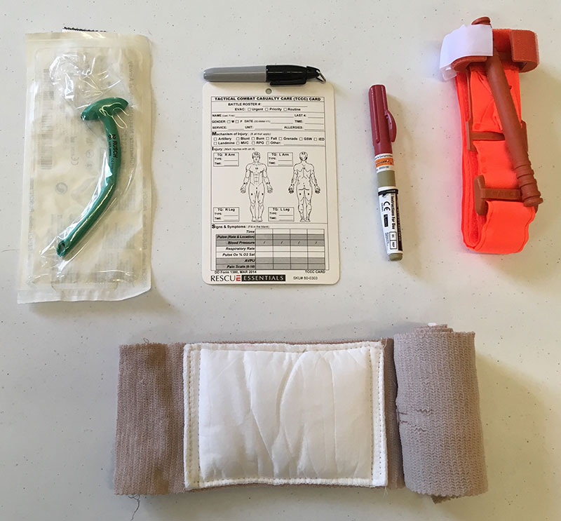 What’s not going on vacation? Nasal Pharyngeal Airway, chest decompression needle, trauma card, and large bandage. Not shown and also not going are space blanket and gloves.