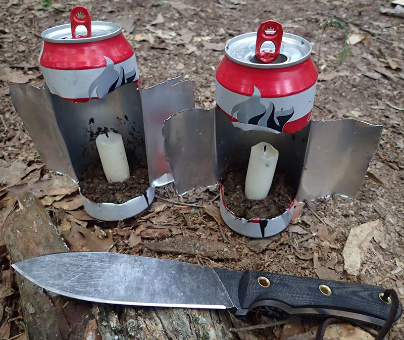 Two discarded beer cans were made into camp lanterns by cutting H shape into the cans and opening them up. Wings can be adjusted to act as wind covers.