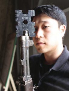 Technician gauges muzzle of one of M1 rifles.