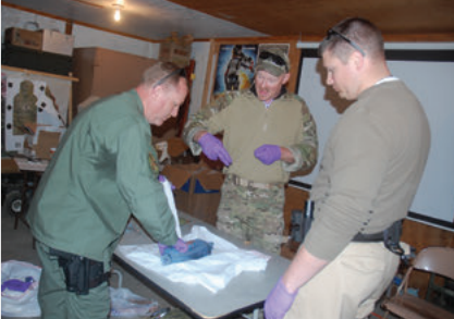 Doc Spears, a former 18D and now a spinal surgeon, supervises students as they learn to pack a gunshot wound in a roast.