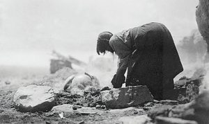 In-this-1906-photo,-legendary-Hopi-potter-Nampeyo-builds-kiln-around-pottery-to-be-fired,-using-broken-pottery-shards-and-suitable-stone