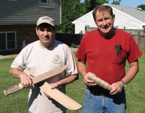 Keller-holds-nearly-completed-KA-BAR-and-sheath-in-poplar,-while-Skaggs-holds-unfinished-KA-BAR-grip