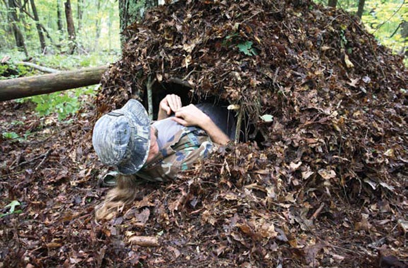 Survival-student-Derrick-Underwood-crawls-feet-first-into-his-completed-debris-hut