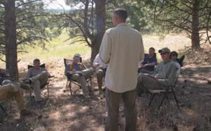 Students-listen-as-Caylen-Wojcik-conducts-classroom-session-under-Ponderosa-pines-that-ring-Central-Cascade-Precision-range.